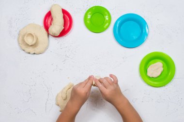 Çocuk elleri tuz hamurundan şekillendirilir. Ellerin iyi motor becerilerinin gelişimi. Çocukların yaratıcılığının gelişimi. Çok renkli tabaklar.