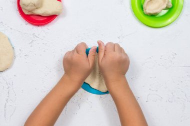 Çocuk elleri tuz hamurundan şekillendirilir. Ellerin iyi motor becerilerinin gelişimi. Çocukların yaratıcılığının gelişimi. Çok renkli tabaklar.