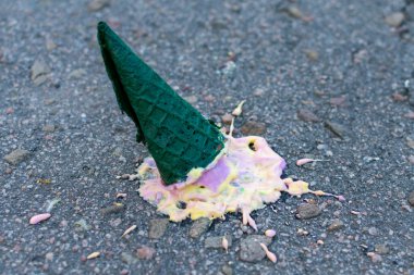 Yeşil külahta parlak dondurma asfalta düştü. Yan görüş. Yakın plan..