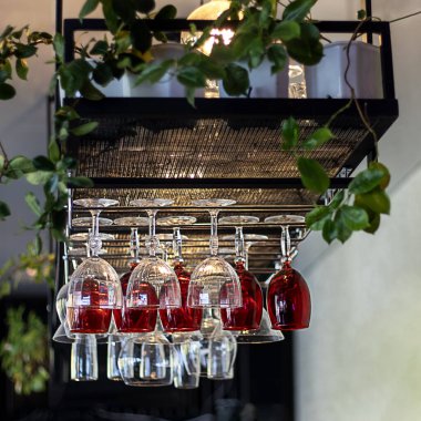 Asılı şarap kadehleri ve yemyeşil zümrüt şık bir bar dekoru oluşturur.