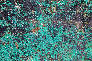Çatlak, pas desenli, turkuaz kabuklu ve desenli yüzeyi olan bir duvarın yakın çekimi..