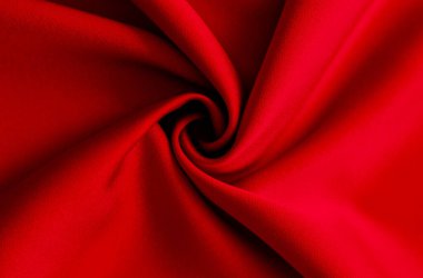 Kalın kırmızı kumaş girdabı zengin doku ve derinliğe sahip dramatik ve soyut bir arkaplan yaratır..