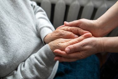 Evde şefkati, rahatlığı, desteği ve güvenilir dostluğu ileten bir bakıcının yaşlı elleri..