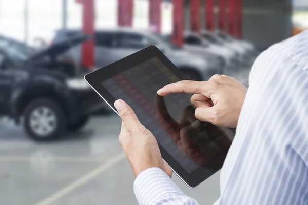 Närbild av en man kontrollera bilen på pekskärm tablet i ett garage — Stockfoto