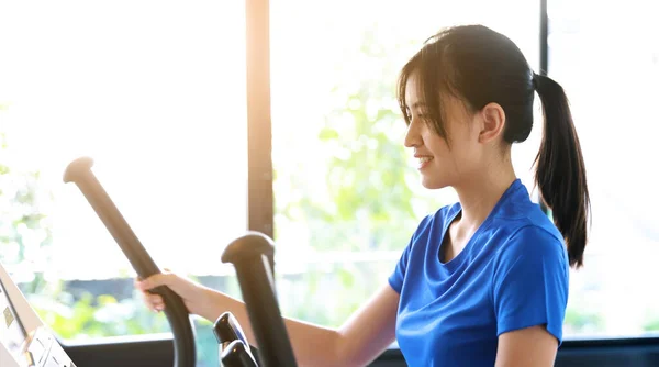 Asian woman exercise on elliptical machine in a gym