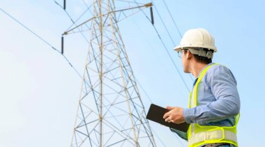 Elektrik Mühendisi Elektrik Santrali Arkaplanı ile Dijital Tablet üzerinde çalışıyor