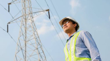 Elektrik mühendisi standı ve elektrik direğinde çalışıyor.