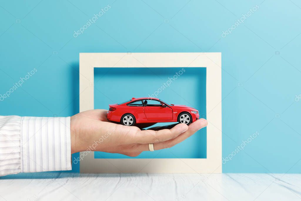 businessman hand holding a car model, insurance concept