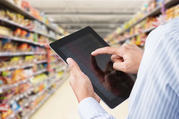 Businessman checking inventory in minimart on touchscreen tablet — Stock Photo, Image