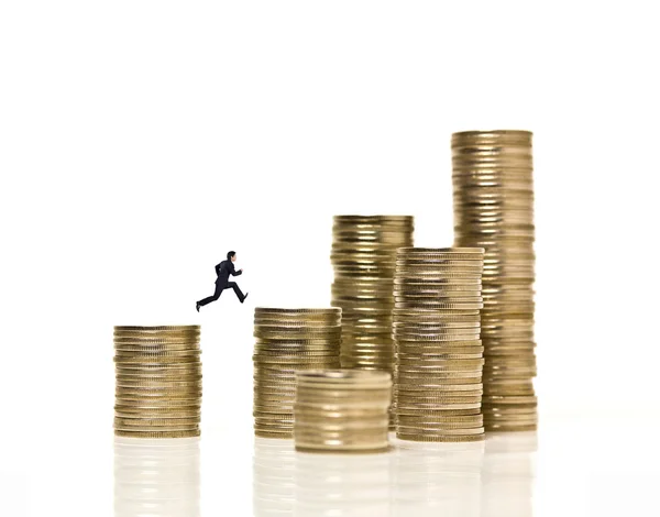 Empresário salta sobre pilhas de moedas — Fotografia de Stock