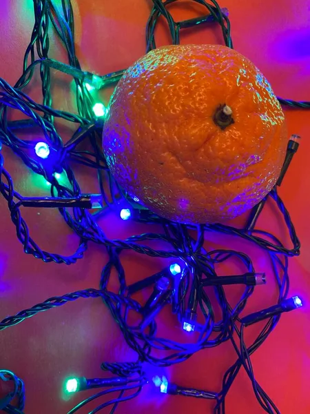 Fesitve Christmas background with garland lights and tangerine — Stock Photo, Image