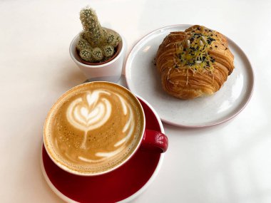 Kahve fincanı, çörek ve bir saksı.