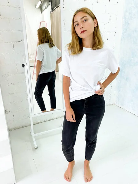 Schöne junge Frau in weißem T-Shirt und schwarzer Jeans — Stockfoto