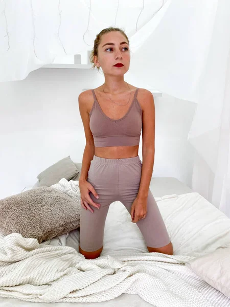 Schöne junge Frau im Bett trägt Sport-BH und knielange Leggings — Stockfoto