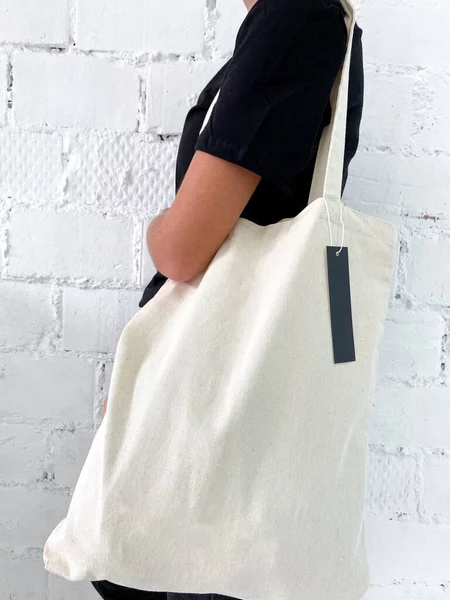 Hermosa mujer joven en camiseta negra y jeans sosteniendo una bolsa de mano o shopper — Foto de Stock