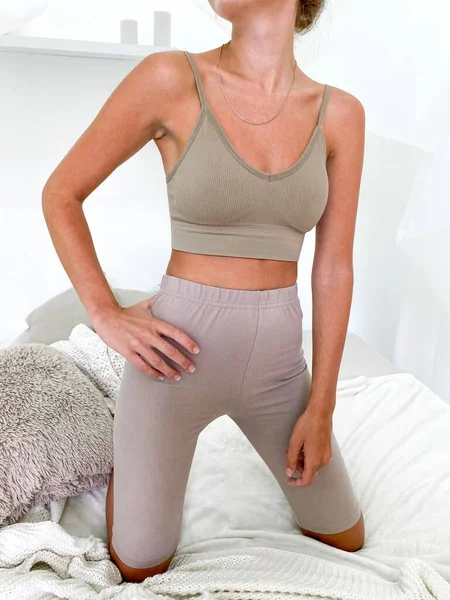 Schöne junge Frau im Bett trägt Sport-BH und knielange Leggings — Stockfoto