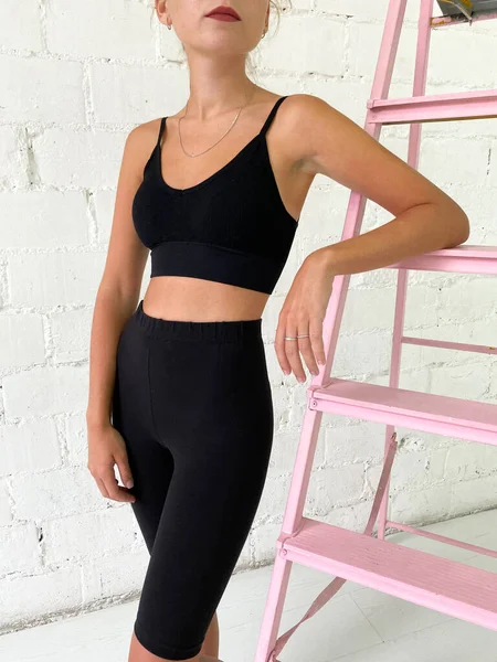 Schöne junge Frau trägt schwarzen Sport-BH und knielange Leggings — Stockfoto