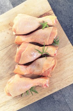 Kırsal arka planda çiğ tavuk budu, biber ve maydanoz.