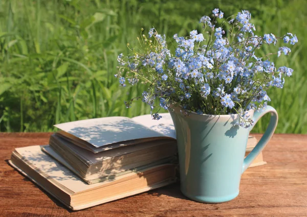 Μπλε κανάτα με μπουκέτο από forget-me-nots σχετικά με ξύλινο τραπέζι και το — Φωτογραφία Αρχείου