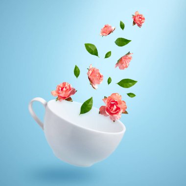 Pembe çiçekler ve yeşil yapraklar beyaz bardaktan uçar..