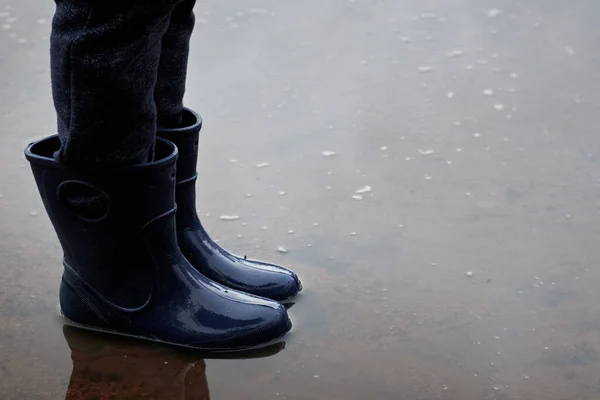 ブーツの子供の足は水たまりの中に立つ — ストック写真