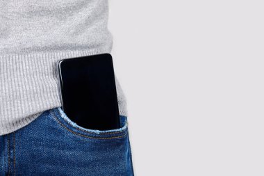 Gri üzerinde kot pantolon cebinde cep telefonu.