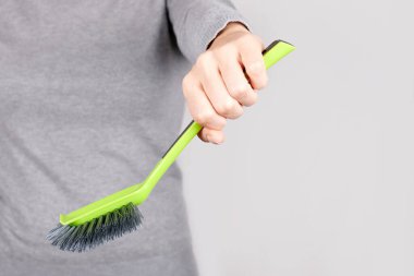 Gri üzerinde yeşil temizlik fırçası olan el..