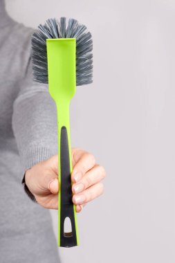 Gri üzerinde yeşil temizlik fırçası olan el..