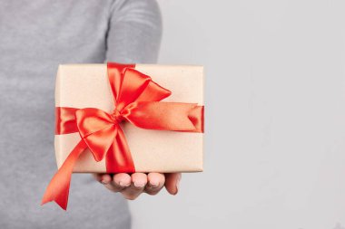 Gri arkaplanda hediye kutusu olan el..