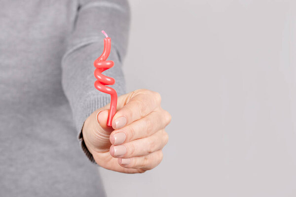 Hand with red candle on grey.