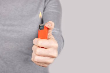 Gri üzerine kırmızı alev çakmağı olan el..