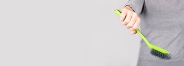 Gri üzerinde yeşil temizlik fırçası olan el..