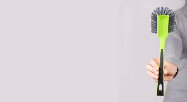 Gri üzerinde yeşil temizlik fırçası olan el..