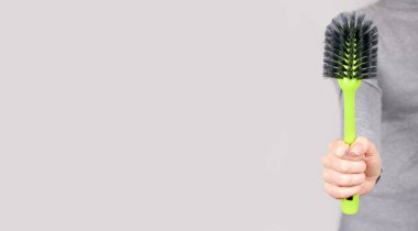 Gri üzerinde yeşil temizlik fırçası olan el..