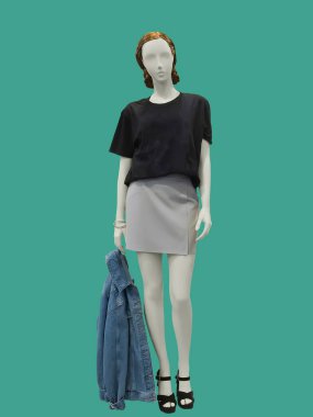 Yeşil arka planda izole edilmiş, gündelik kıyafetler giymiş tam boy kadın mankeni. Marka isimleri veya telif hakkı nesneleri yok.
