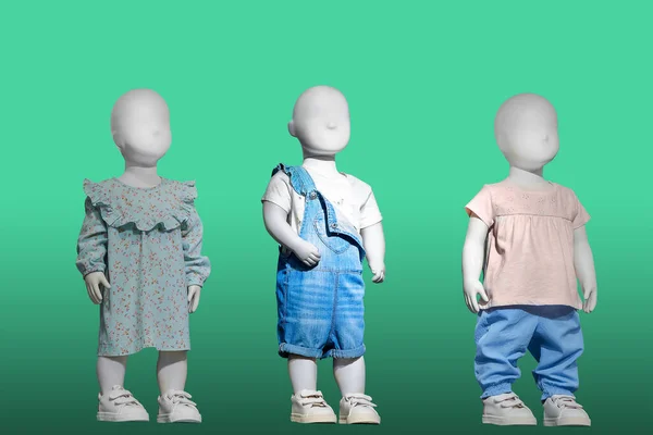 三个穿着时髦童装的人体模特被绿色背景隔离了没有商标名称或版权对象 图库照片