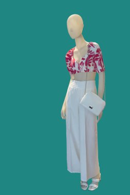 Yeşil arka planda izole edilmiş şık yaz kıyafetleri giyen bir kadın vitrin mankeni..