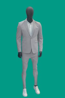 Yeşil arka planda izole edilmiş gri takım elbiseli bir erkek vitrin mankeni..