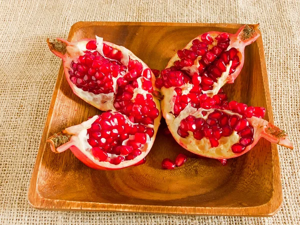 Open pomegranate on wooden plate — Stock Photo, Image