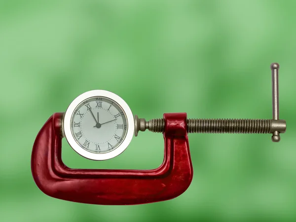 Clock squeezed with clamp. Royalty Free Stock Images