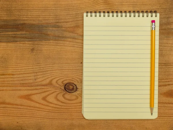 Cuaderno y lápiz sobre tabla de madera — Foto de Stock