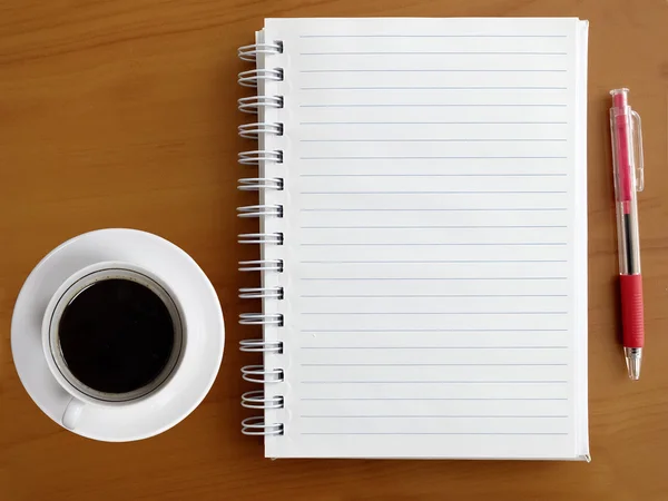 Notebook, caneta e xícara de café na mesa de madeira — Fotografia de Stock