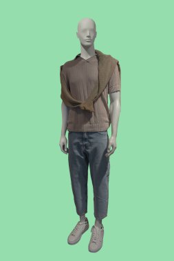 Beyaz arka planda, kısa kollu ve gri kotlu kahverengi hırka giyen bir erkek mankenin tam boy görüntüsü.