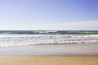 Dalgalar usulca ıssız deniz kıyısına yuvarlanıyor.