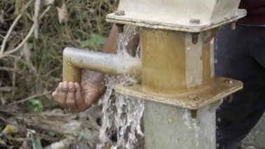 Hindistan 'daki bir kamu pompasından su almak için uzanan el.