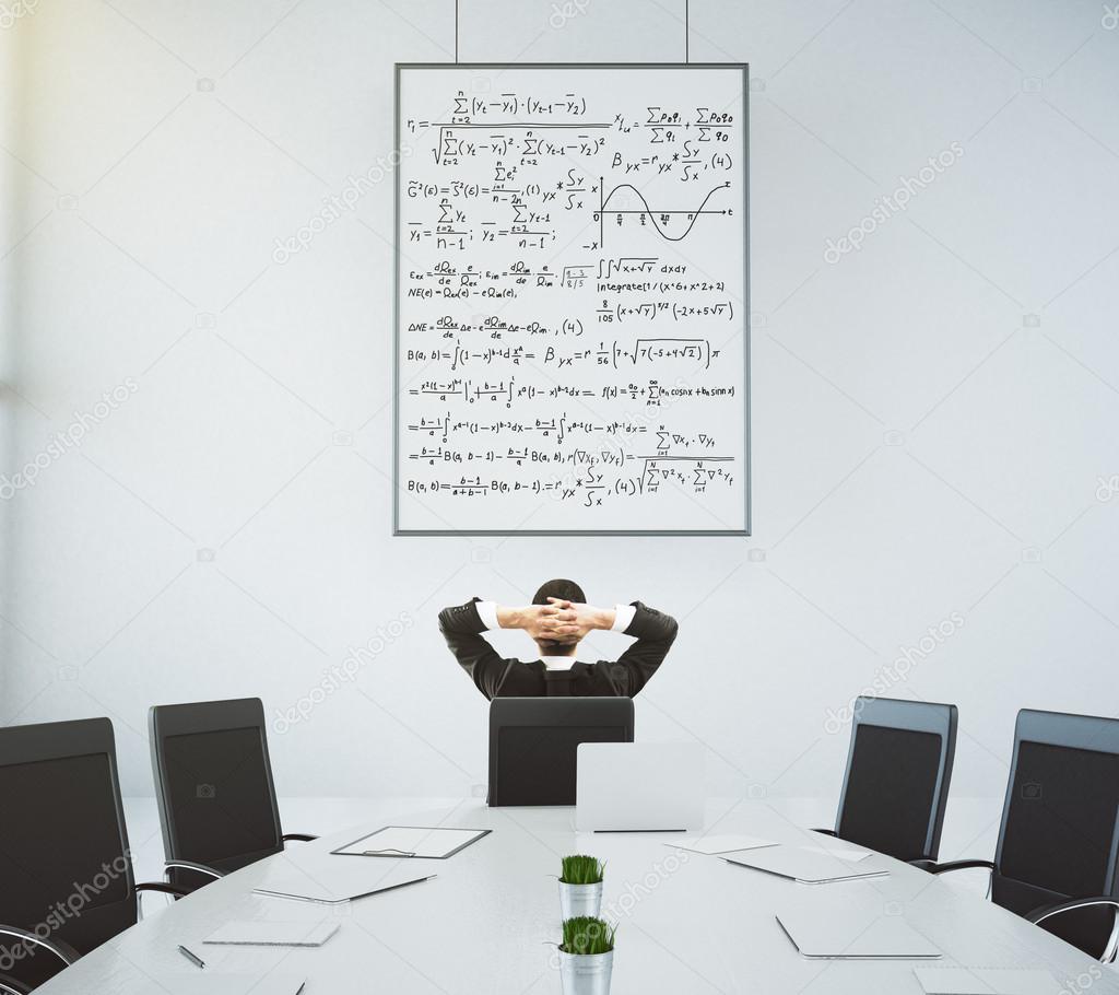 Businessman looks at the poster with equations in modern confere