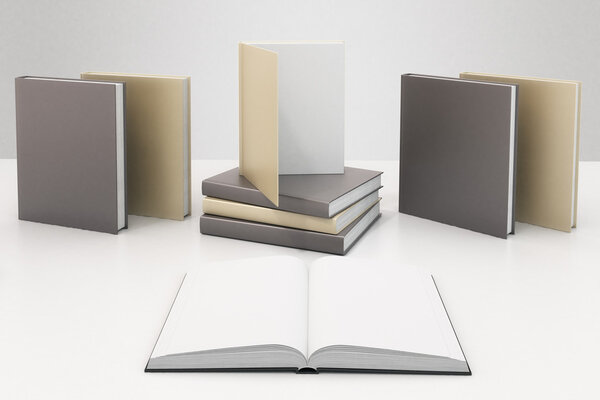Blank book pages on white table with other books with blank cove