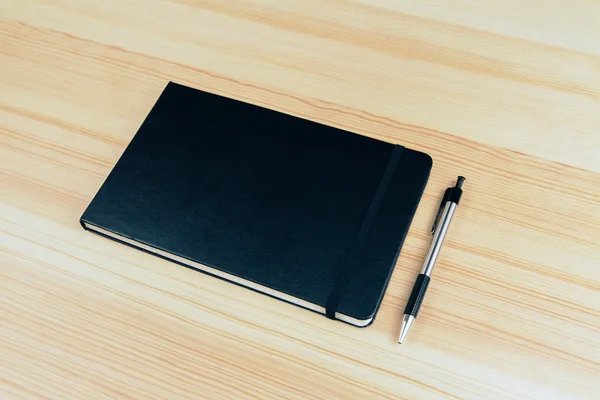 Чистый чехол блокнота с ручкой на деревянном столе, макет — стоковое фото