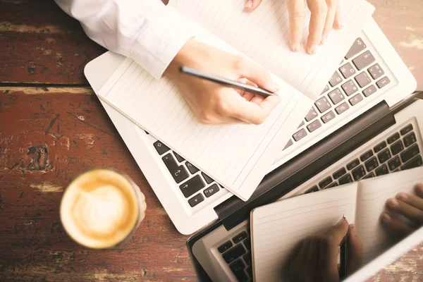 Man händerna skriva i dagboken, kaffekopp och laptop på trä — Stockfoto