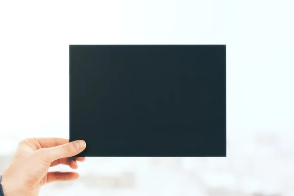 Hand holding black paper sheet — Stock Photo, Image